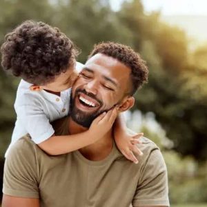 Father, bonding and child hug happy in nature spending quality time together outdoor. Happiness, laughing and family love of a dad and kid in a park enjoying nature hugging with care and a smile